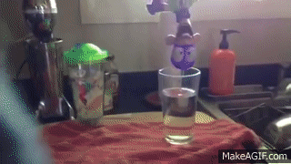 A GIF of a doll of Fanboy being aggressively dunked into a glass of water